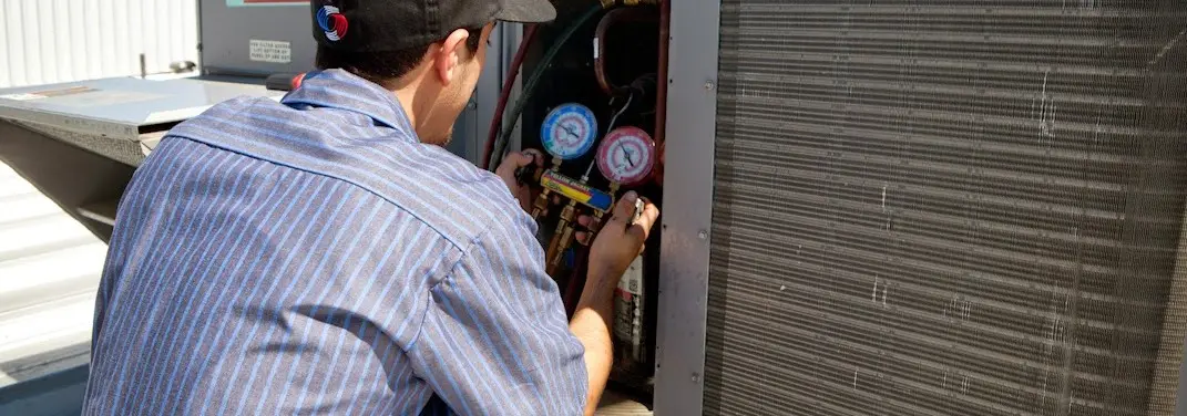 HVAC technician servicing a condenser unit in Wayland